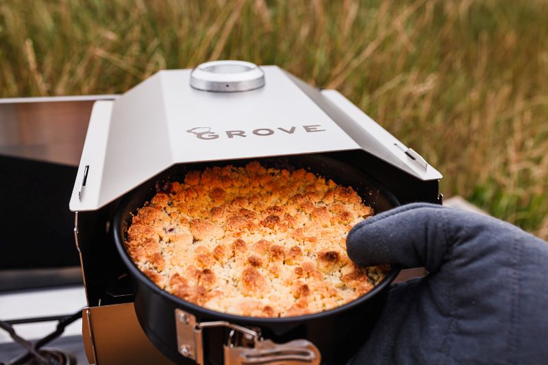 Ambientefoto:
Grove Camping - Horst der multifunktionale Campingofen wie aus ihm grade ein fertig gebackener Kuchen  genommen wird