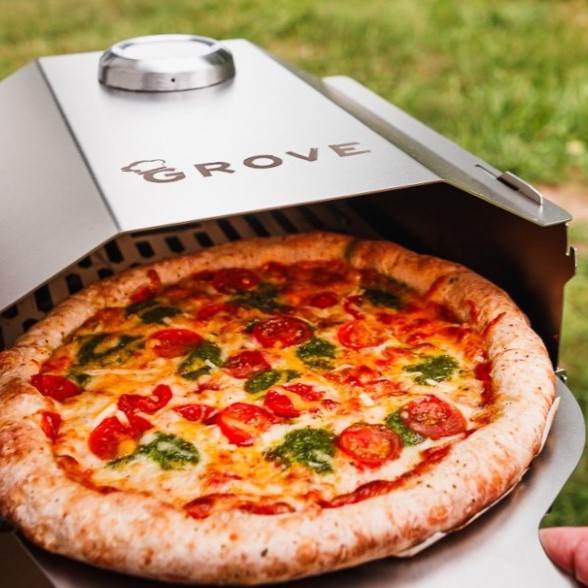 Ambientefoto:
Horst der multifunktionale Campingofen aus dem grade mit dem Grove Pizzaschieber eine Tiefkühlpizza herausgenommen wird mehr aus der draufsicht