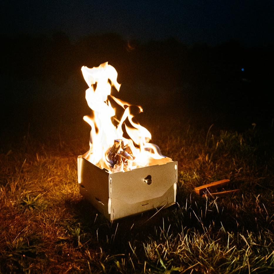Ambientefoto:
Horst der multifunktionale Campingofen als Feuerschale mit brennendem Lagerfeuer auf einer Wiese
