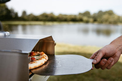 Grove Camping | Campingofen Horst mit Pizza auf dem Pizzaschieber