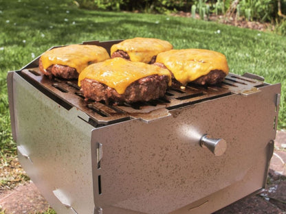 Ambientefoto:
Grove Camping - Horst der multifunktionale Campingofen als Holzkohlegrill beim Grillen von Burgerpattys mit Käse